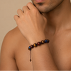 Man wearing a colorful beaded bracelet on a beige background