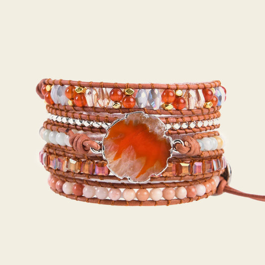 Multistrand bracelet with beads and a central orange stone on a beige background
