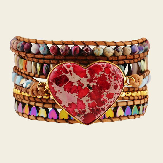 Multicolored beaded bracelet with a red heart charm on a beige background