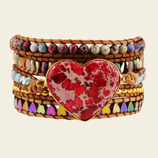 Multicolored beaded bracelet with a red heart charm on a beige background