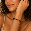 Close-up of a woman wearing a bracelet with beads on a neutral background