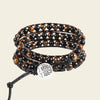 Multilayered beaded bracelet with a central metal charm on a beige background