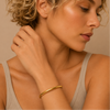 Woman wearing a gold bracelet on a beige background