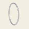 A minimalist, polished silver-toned metal bangle ring shown against a solid, warm off-white background.