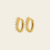 Gold hoop earrings with small diamonds on a beige background