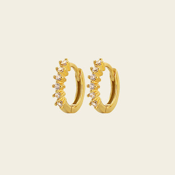 Gold hoop earrings with small diamonds on a beige background