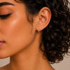 Close-up of a woman wearing a diamond earring with a neutral background
