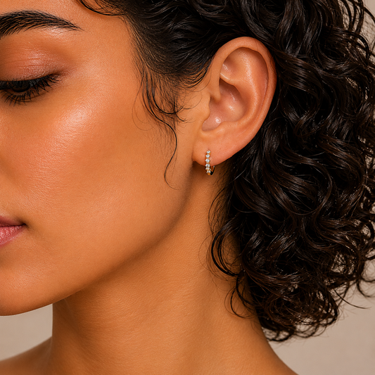Close-up of a woman wearing a diamond earring with a neutral background