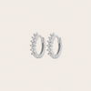Silver hoop earrings with small diamonds on a light beige background