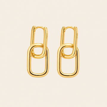 A pair of gold chain-link hoop earrings on a light beige background.