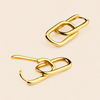 Two gold-toned abstract chain-link earrings with a polished metallic finish, displayed on a light beige background.