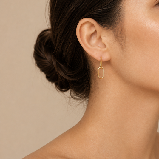 Close-up of a woman wearing a gold hoop earring against a beige background