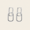 A pair of polished silver drop earrings with interlocking oval link designs, displayed on a solid light beige background.