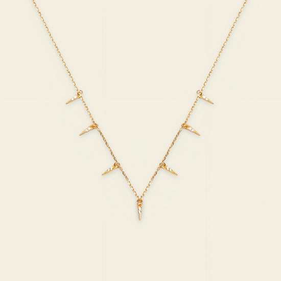 Gold necklace with small pendants on a beige background