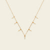 Gold necklace with small pendants on a beige background