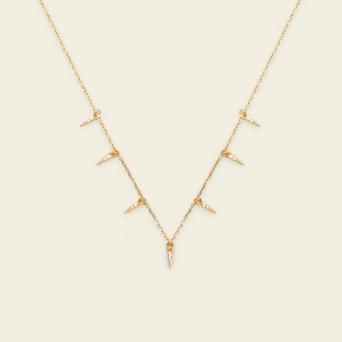 Gold necklace with small pendants on a beige background