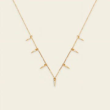 Gold necklace with small pendants on a beige background