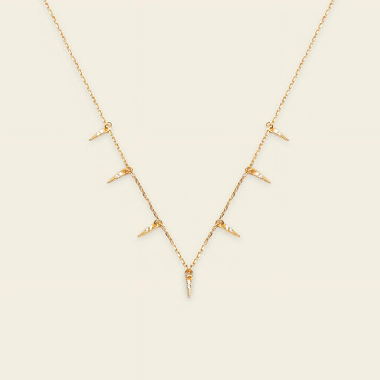 Gold necklace with small pendants on a beige background