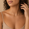 Gold necklace with small pendants on a beige background.