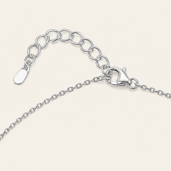 Silver chain necklace with an adjustable lobster clasp and a flat tag, shown on a light cream background.