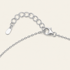 Silver chain necklace with an adjustable lobster clasp and a flat tag, shown on a light cream background.