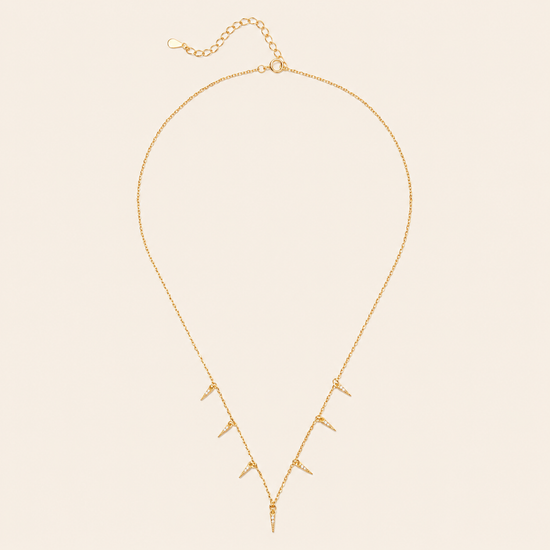 Gold necklace with small pendants on a beige background