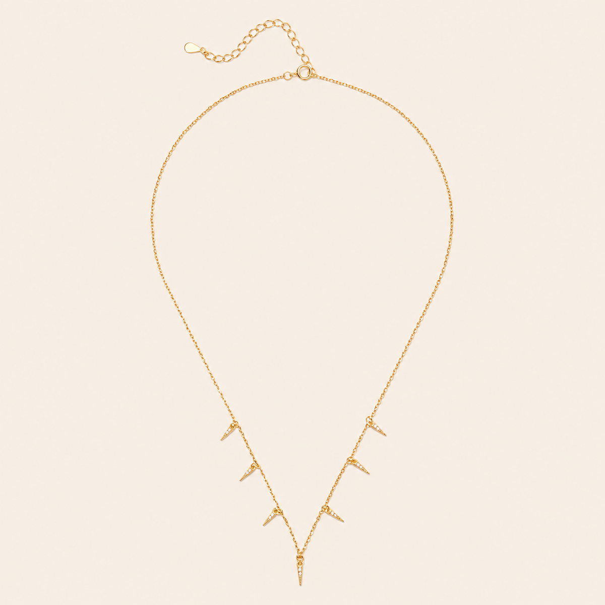 Gold necklace with small pendants on a beige background