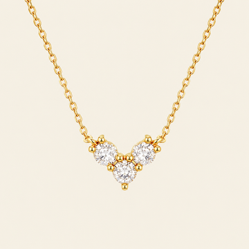 Gold necklace with a V-shaped diamond pendant on a beige background