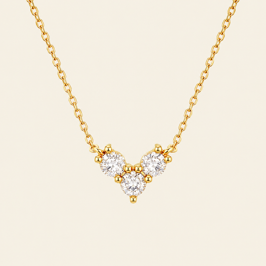 Gold necklace with a V-shaped diamond pendant on a beige background