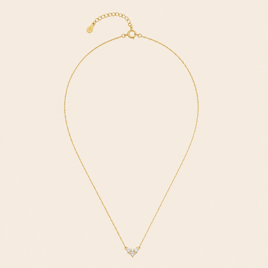 Gold necklace with a heart-shaped pendant on a beige background