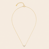 Gold necklace with a heart-shaped pendant on a beige background