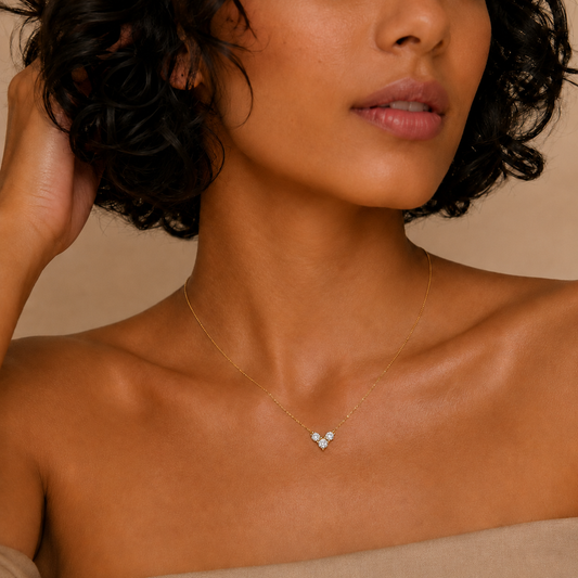 Close-up of a woman wearing a delicate necklace against a neutral background