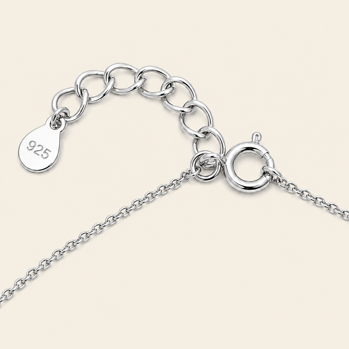 Close-up of a silver chain necklace extender with a lobster clasp and a teardrop-shaped tag engraved with '925' on a light beige background.