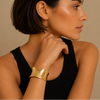 Woman wearing a gold bracelet on a beige background