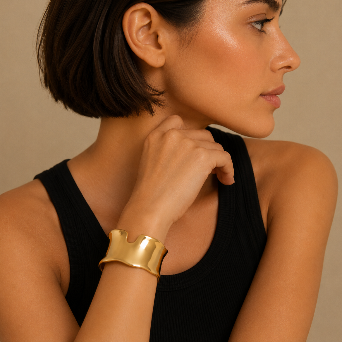 Woman wearing a gold bracelet on a beige background