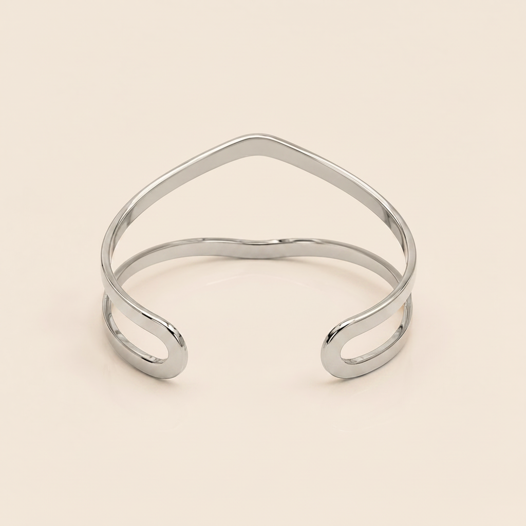 A polished gold open cuff bangle with a wavy, organic line design, photographed on a solid light beige background.