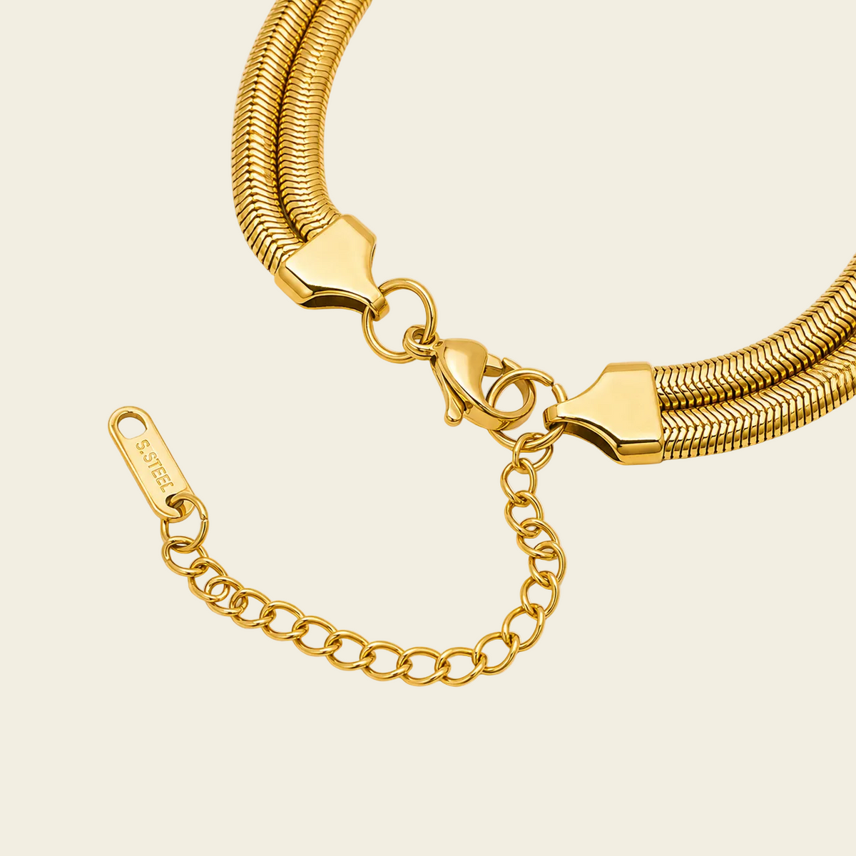 Close-up of a gold snake-chain necklace with a lobster clasp, heart-shaped connector and extender chain.