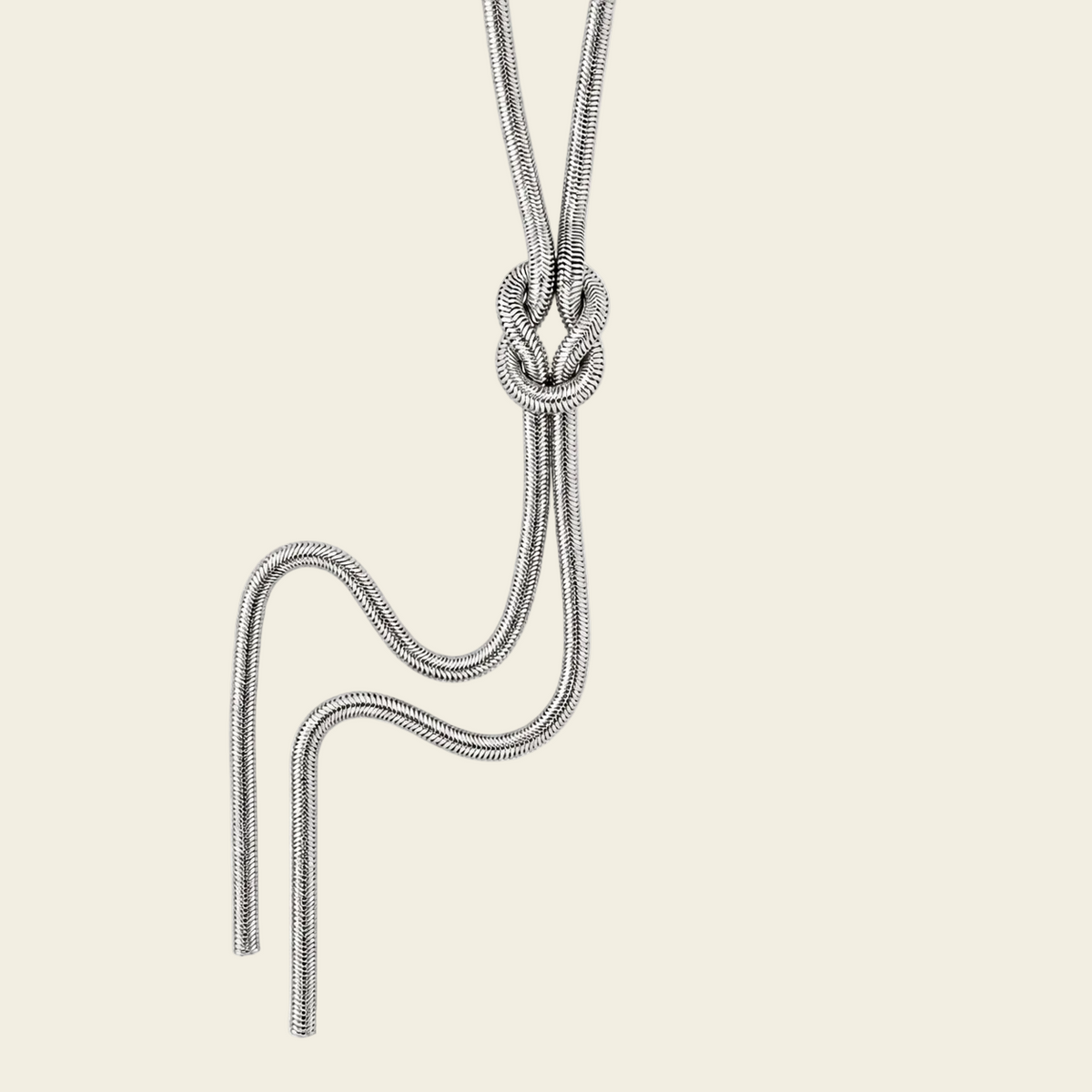 A gold snake chain necklace featuring a decorative knot pendant, shown against a solid pale beige background.