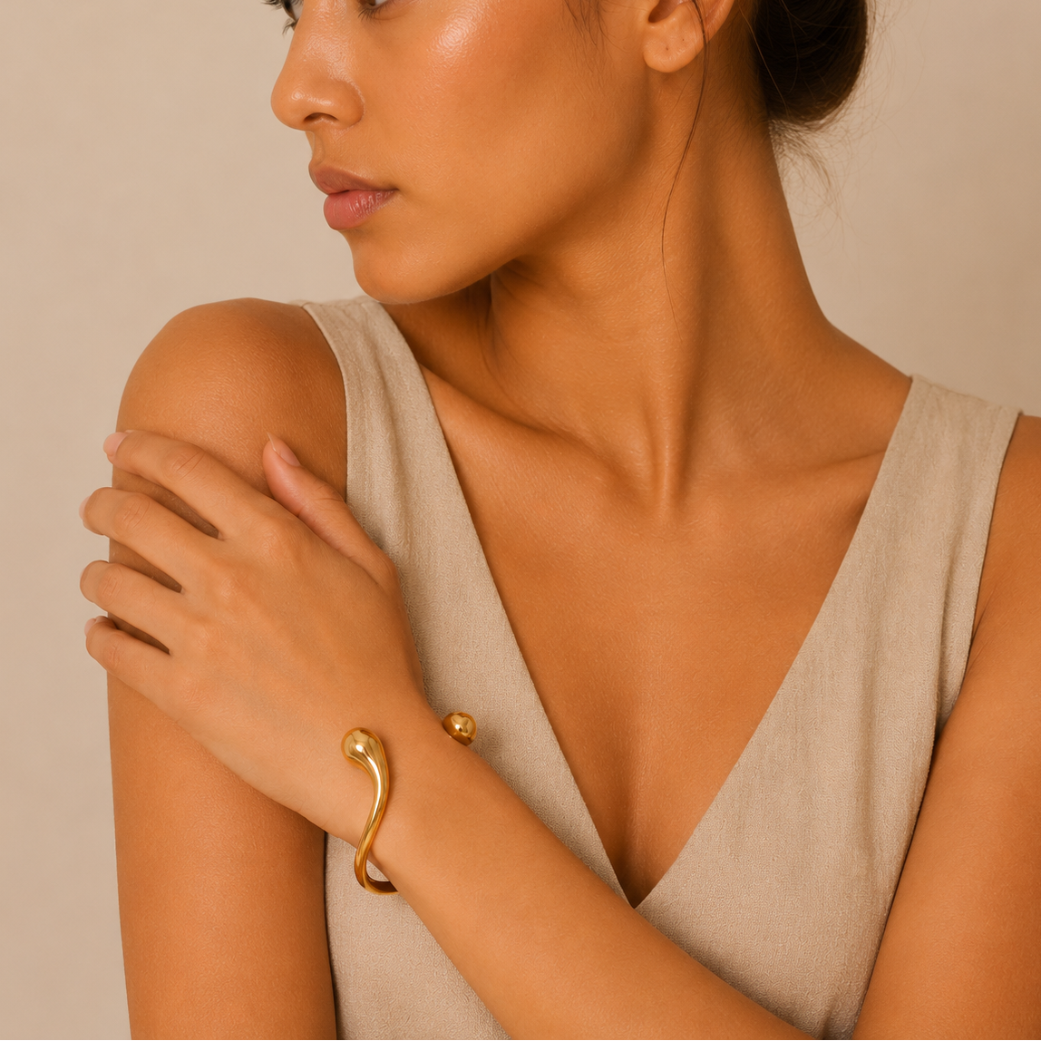 Woman wearing a gold bracelet on a beige background