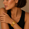 Woman wearing a gold bracelet on a beige background