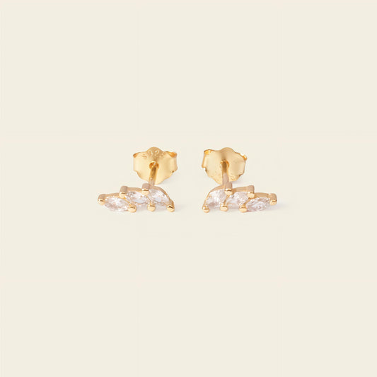 Gold earrings with clear stones on a beige background