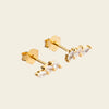 Gold earrings with clear gemstones on a beige background