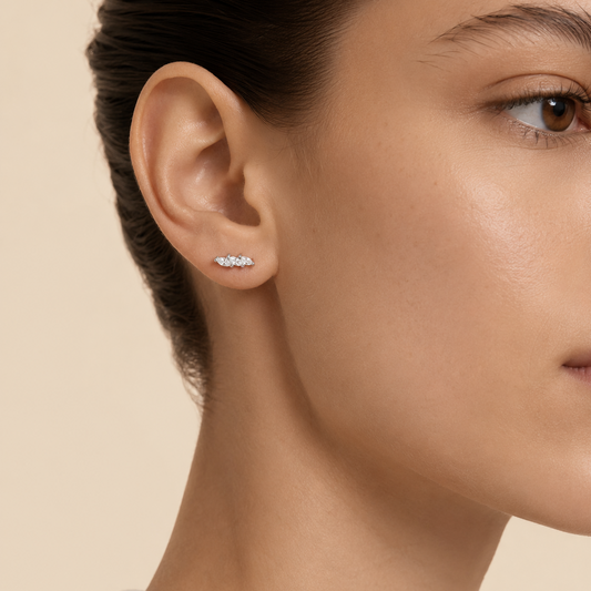 Close-up of a woman wearing diamond stud earrings on a beige background