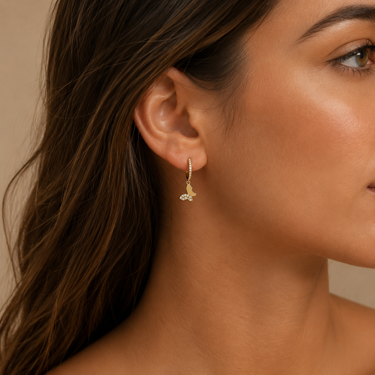 Close-up of a woman wearing gold earrings with a neutral background