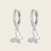 Silver hoop earrings with crescent moon designs on a light beige background