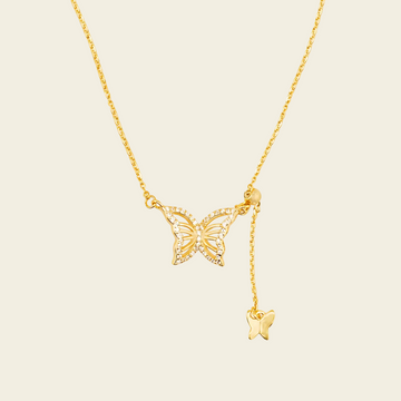 Gold butterfly necklace on a beige background