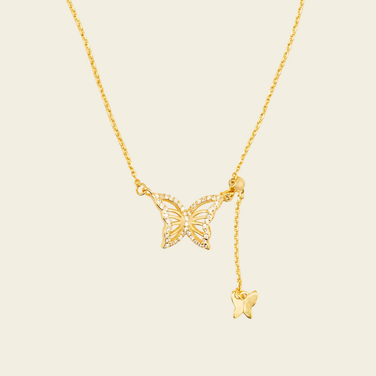 Gold butterfly necklace on a beige background