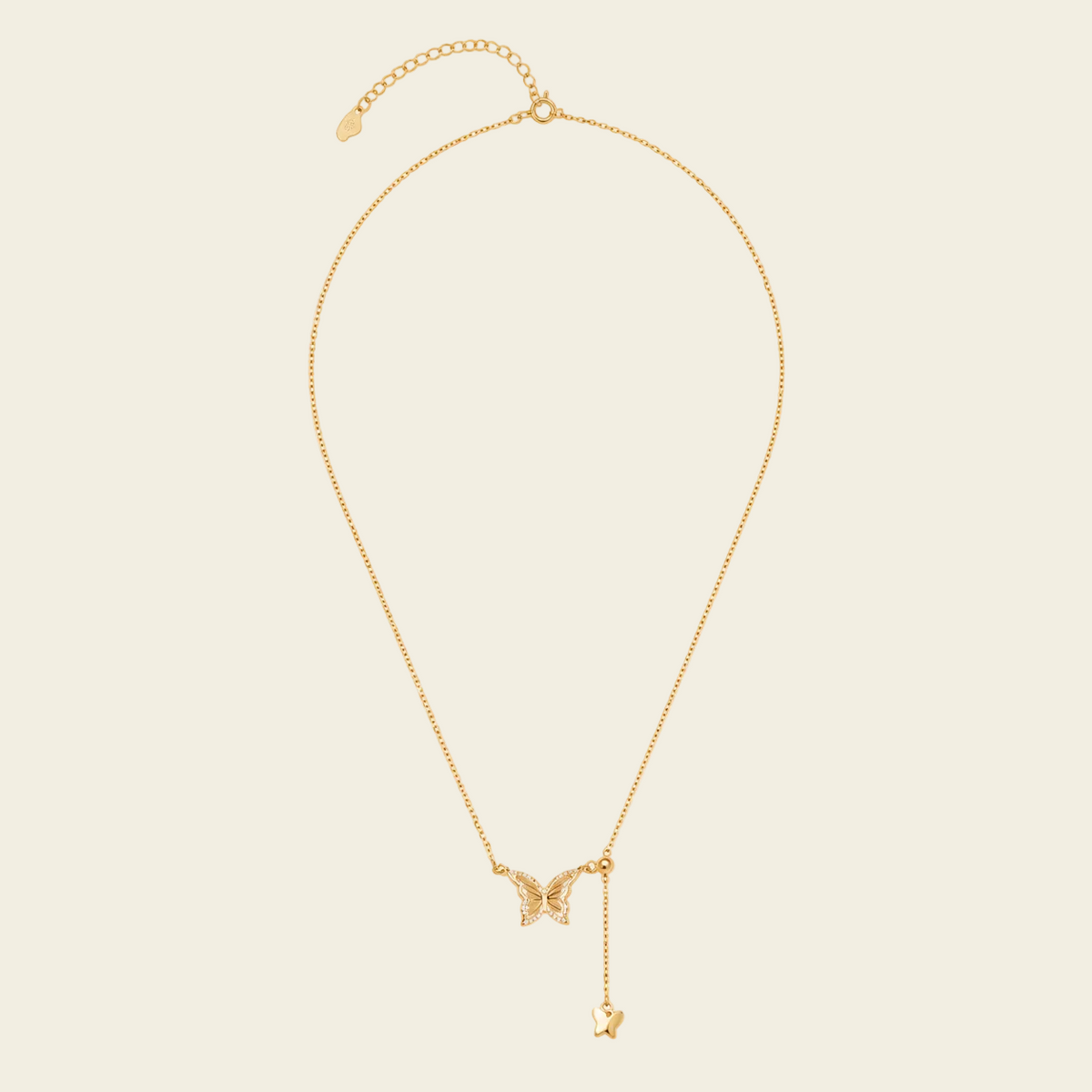 Gold necklace with a butterfly pendant on a beige background