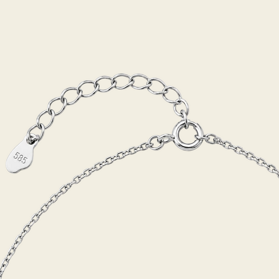 Close-up of a silver chain necklace on a light beige background.