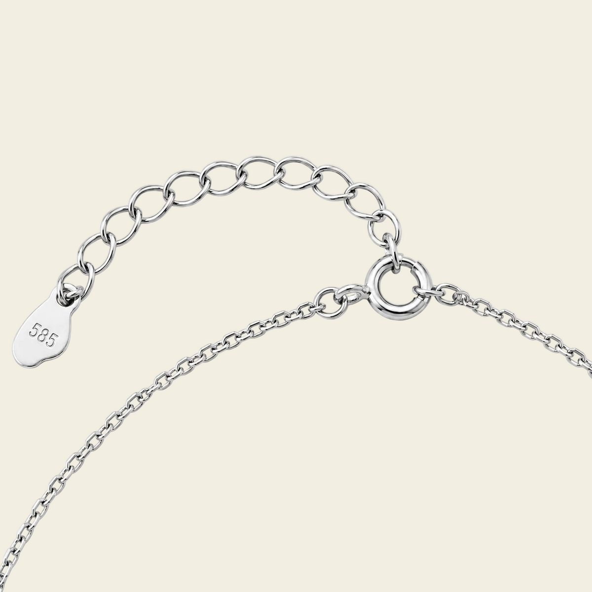 Close-up of a silver chain necklace on a light beige background.
